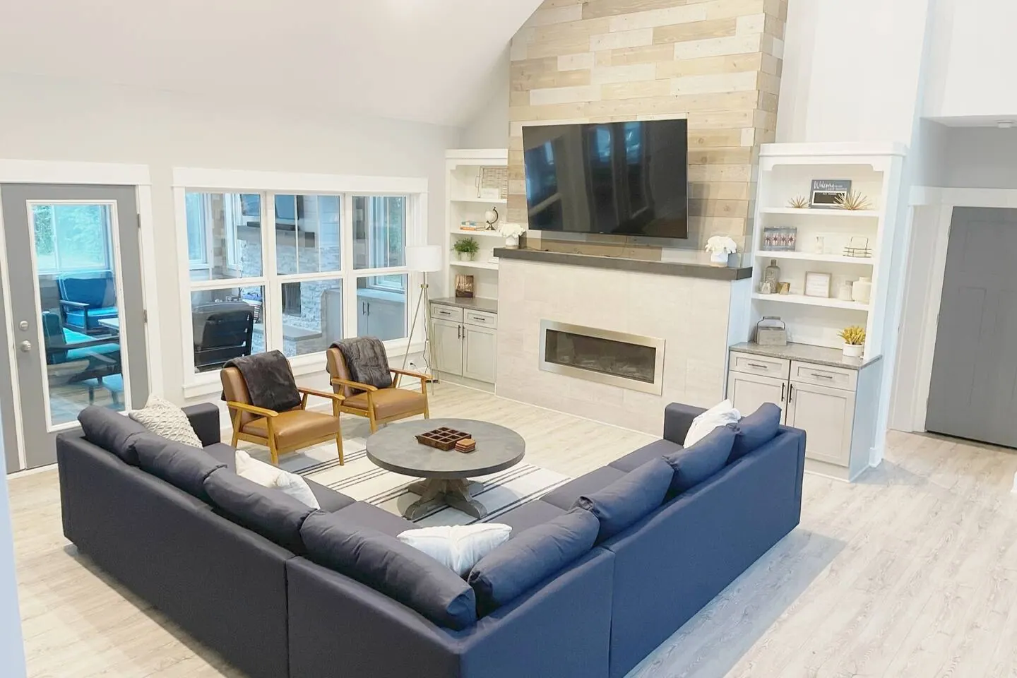 Grand living room with a large sectional, fireplace, and wall of windows