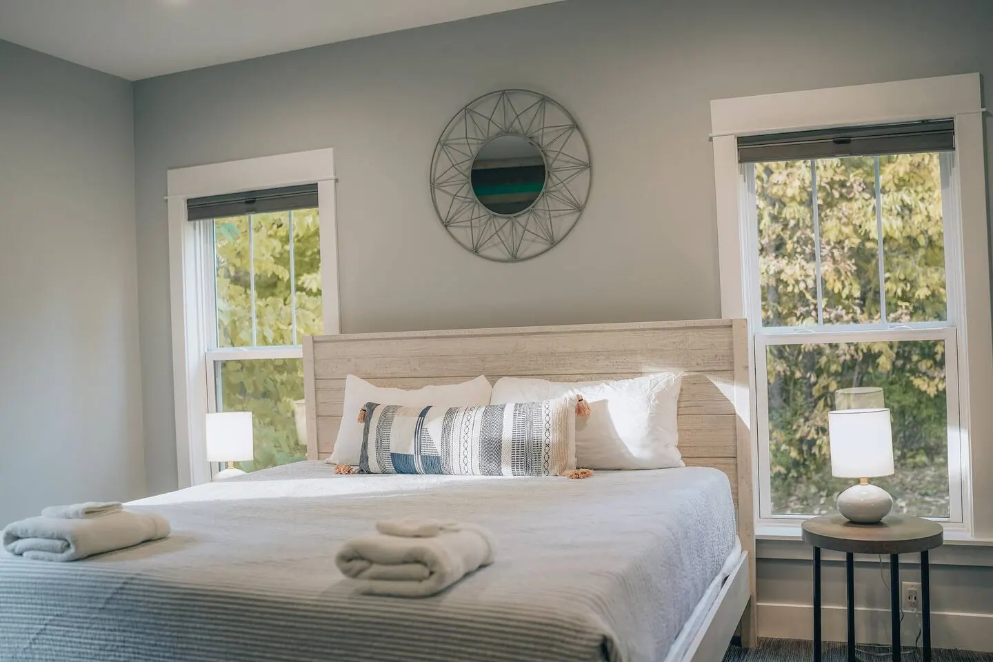 Bedroom with an upholstered king bed and a round mirror